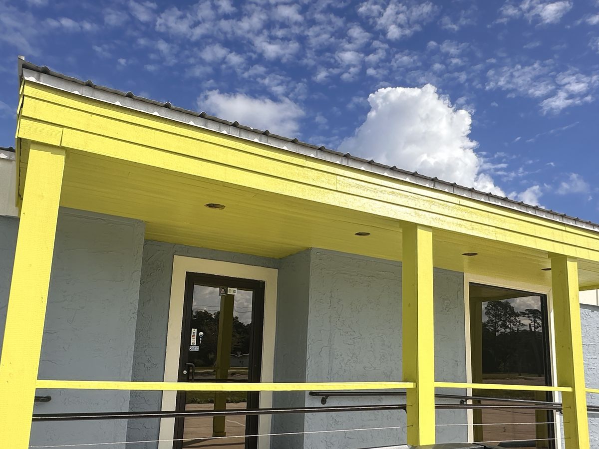 The front entrance under a lime-green porch roof with lime posts and railings